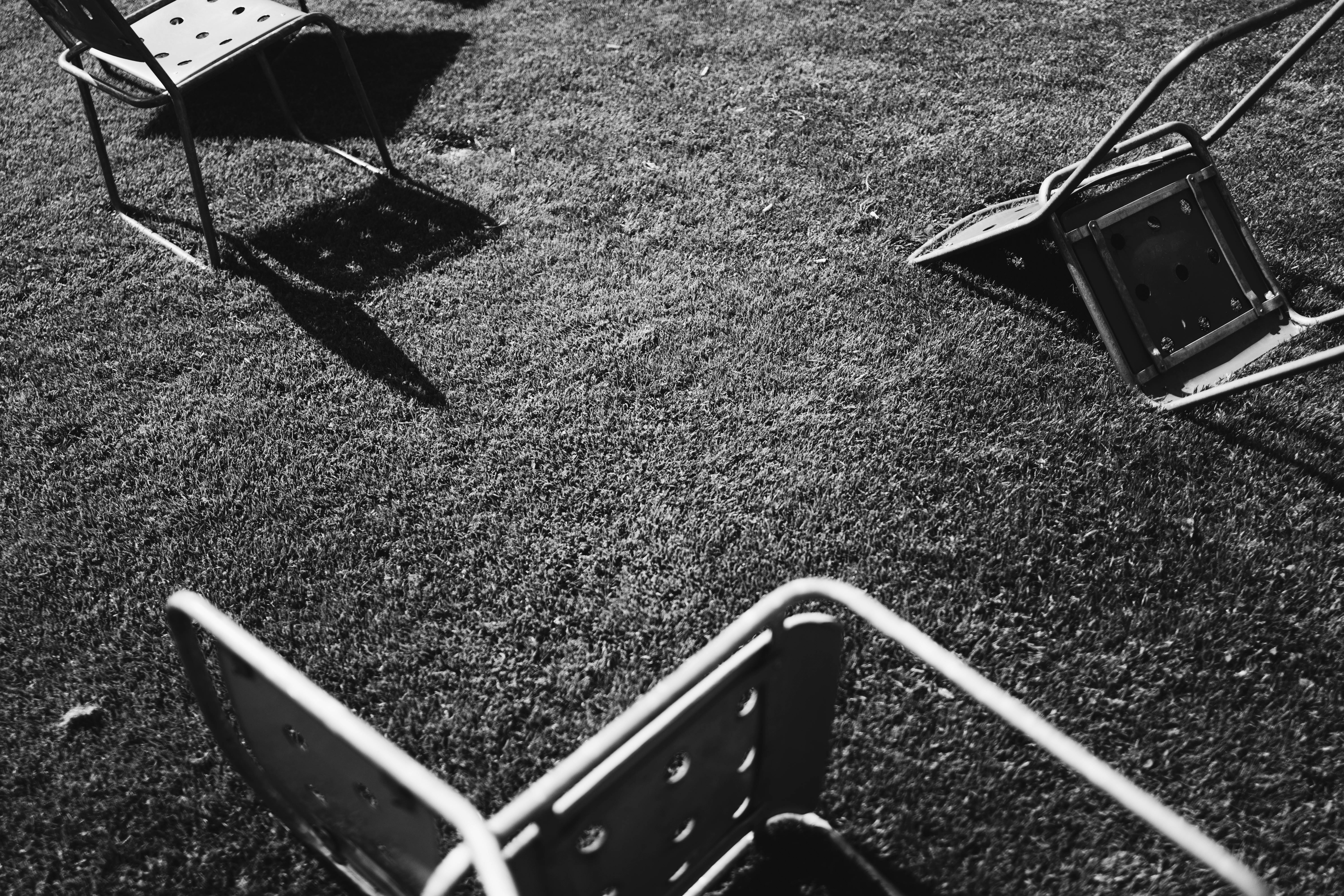 grayscale photo of gray chairs on grass field